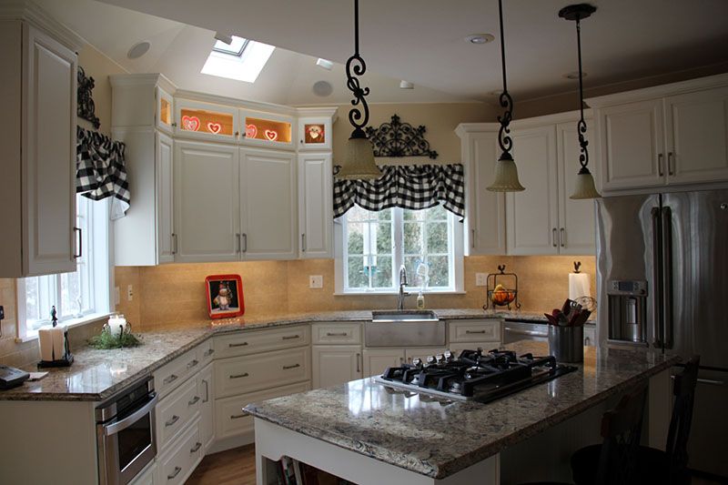 farm-style kitchen with white cabinets stretching to the ceiling and island