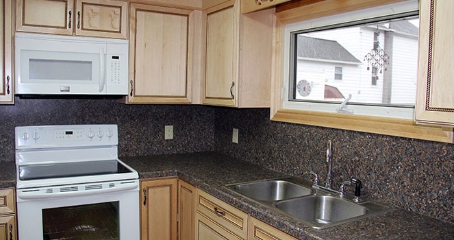 remodeled kitchen with white cabinets, a large window above sink and matching countertops with backsplash