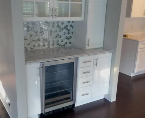 kitchen remodel with white cabinets matching countertops and patterned backsplash